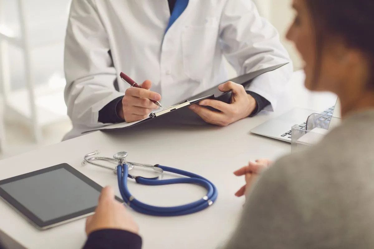 Médico anotando informações durante consulta com paciente